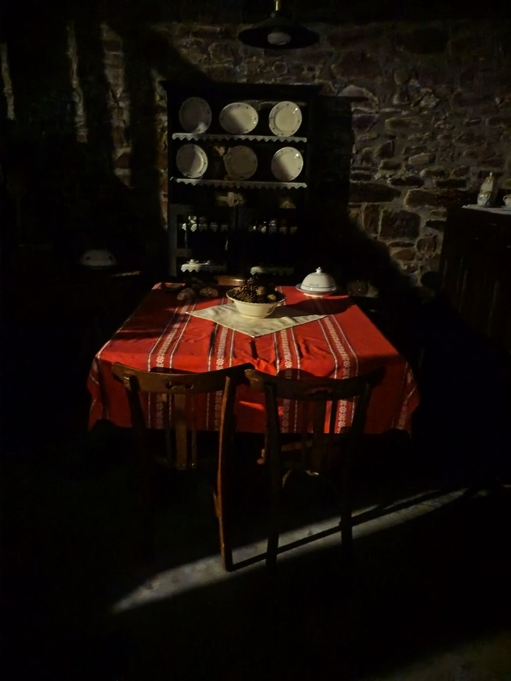 XX. mendeko sala bateko mobiliarioa, egur iluneko muebleak, mantel gorria, plater txuriak.