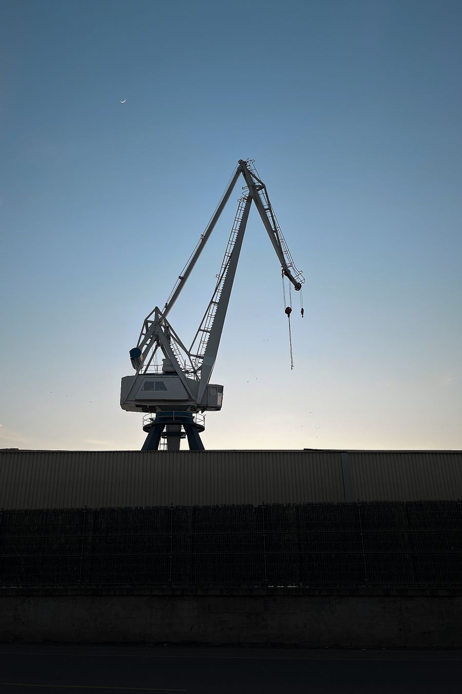 Ontziola bateko garabiaren silueta, ilunabarrean, atzean zeru urdina eta ilgora dituela.